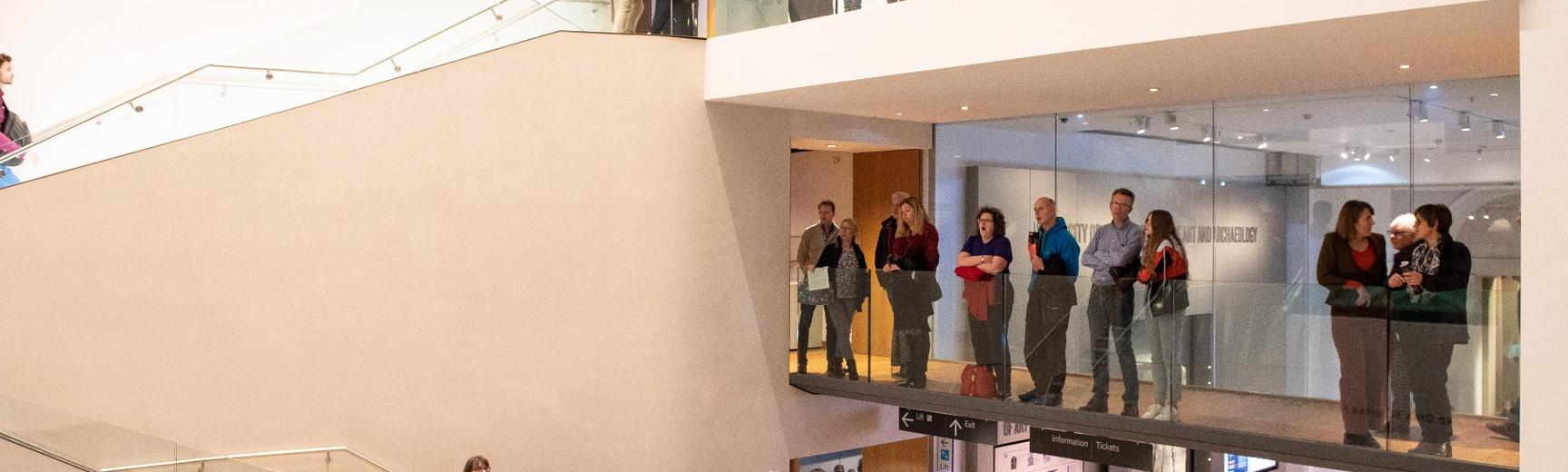People standing on a balcony at the Ashmoleum Museum viewing an exhibition that is out of frame