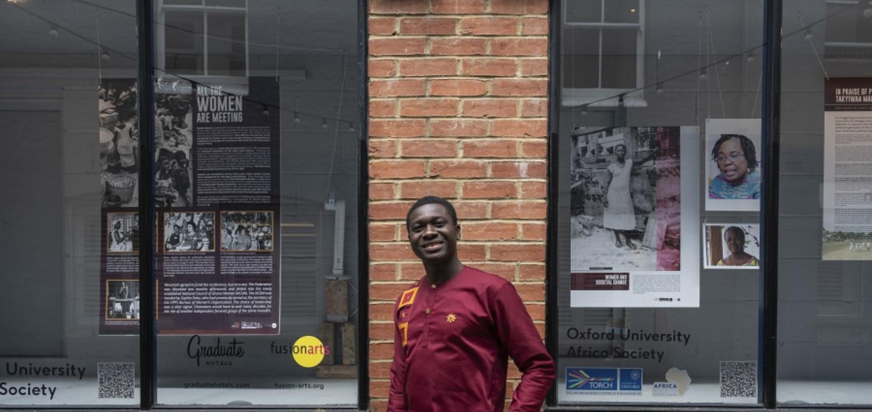 man in red shirt smiling in front of window display