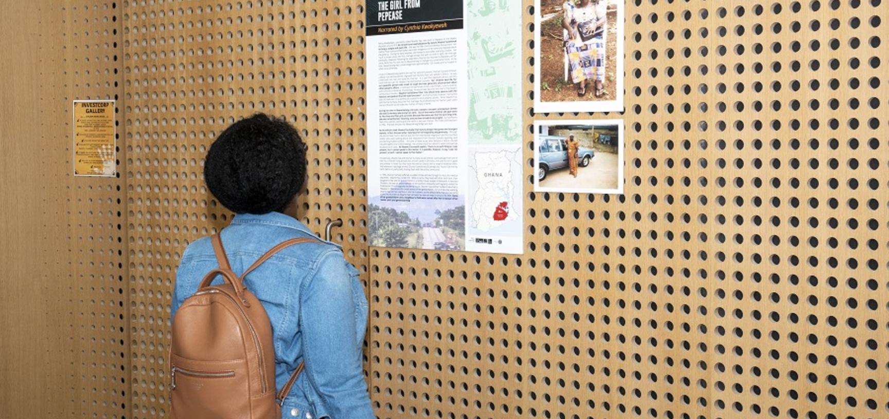 woman looks at poster on a wooden wall