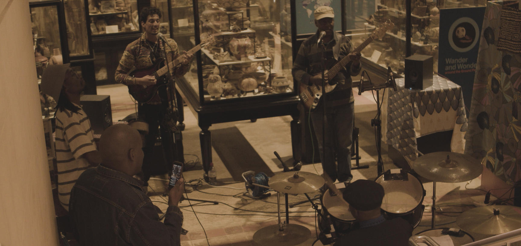 Four musicians play in the middle of Pitt Rivers Museum amoungst the artifact cases