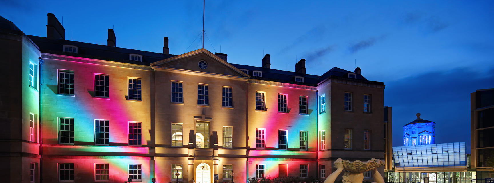 Radcliffe Humanities Building at night with rainbow lights projected on to it