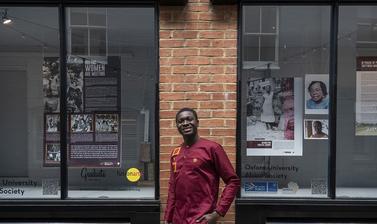 man in red shirt smiling in front of window display