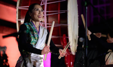 A woman smiling playing the drums