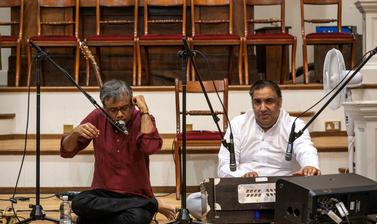 singer Amit Chaudhuri sitting on stage with two musicians 