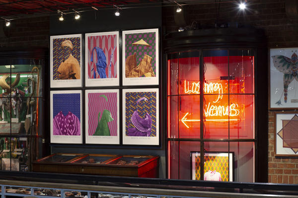 Colourful display showing neon red lights, with 6 prints of indigenous clothing