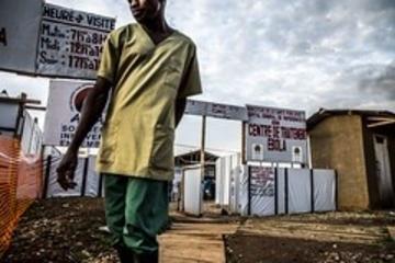 Person standing in front of a centre for ebola treatment with white plastic signs