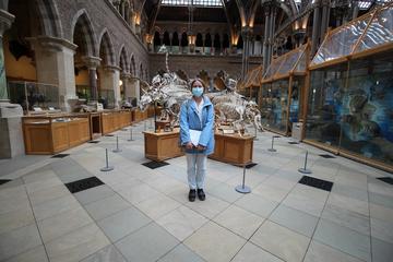 woman in blue stands in front of dinosaur bones in Oxford Natural history Museum