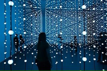 Silhouette of a figure in a dark blue, mirrored room with strings of lights