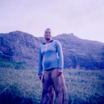 Blurred image of woman standing over camera with backdrop of forest and mountains