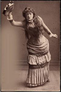 Monochrome image depicts Adeleide Johannessen in character as Nora dancing the tarantella dance and holding, above her head, a tambourine in her right hand.