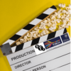 Image displays a clapboard on a yellow background with scattered popcorn between the open clap. Clapboard by GR Stocks on Unsplash